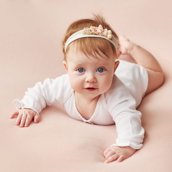 girl-four-months-lies-light-pink-background